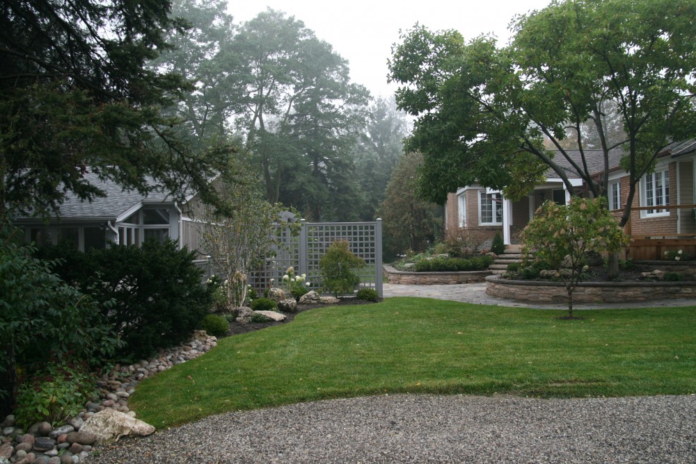 This was an extensive project to update the existing landscaping. Overgrown trees and shrubs were removed. The crumbling retaining walls were replaced. A fence, arbor and columnar beeches were added to block the view of the adjacent house. A courtyard patio was created with a privacy fence to screen the side yard from the road. A fountain, a teak bench and an oversize urn complete the seating area. New plantings were installed throughout.