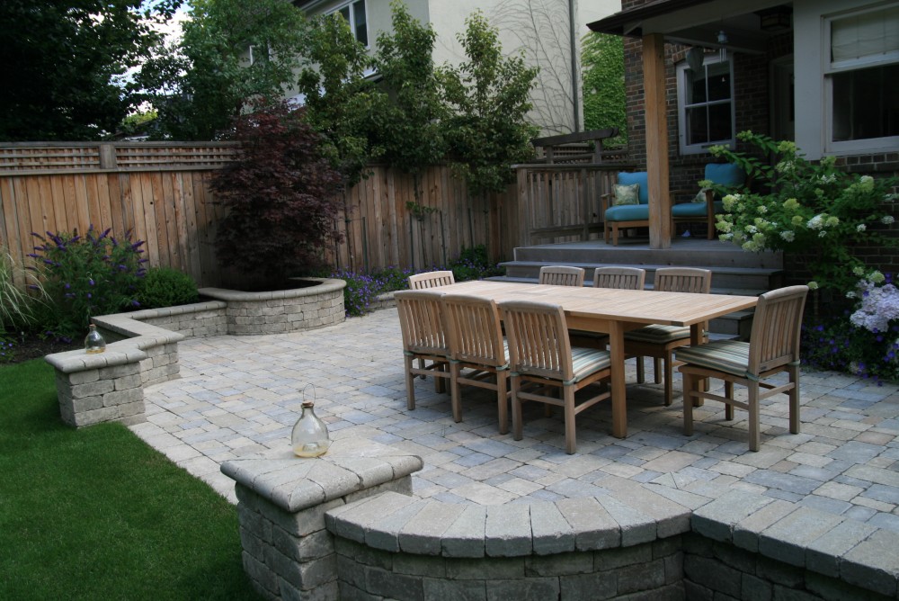 We transformed this back yard by removing an old unused garage and reclaiming part of the driveway. The client wanted a large patio to to hold a sizable table for family gatherings. Incorporating a seating wall into the patio design provides extra seating for entertaining. A small corner shed from Summerwood adds to the aesthetics. A new fence and columnar pears provide privacy.